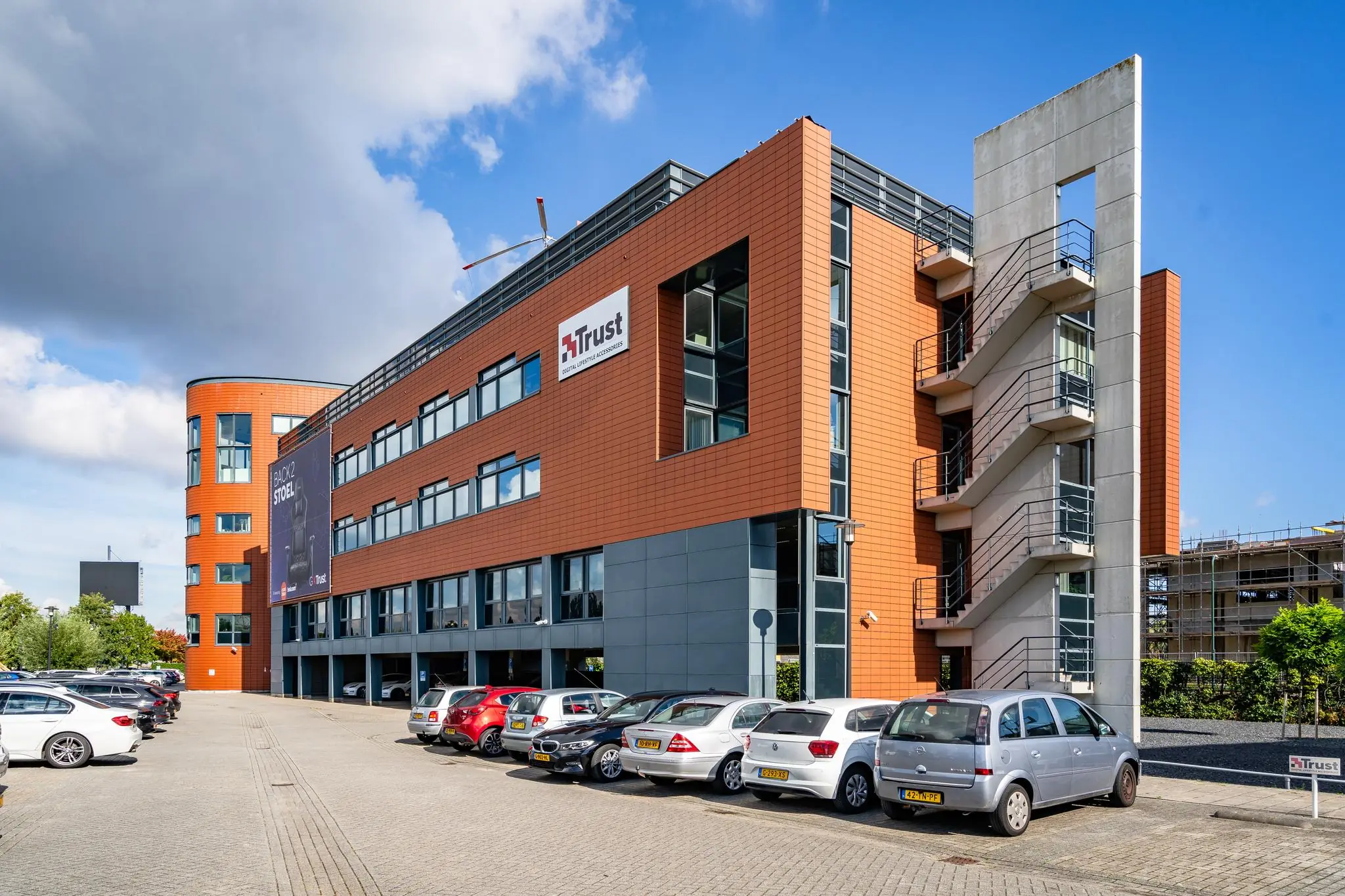 Kantoorgebouw van Trust aan de Laan van Barcelona met geparkeerde auto's op de voorgrond.